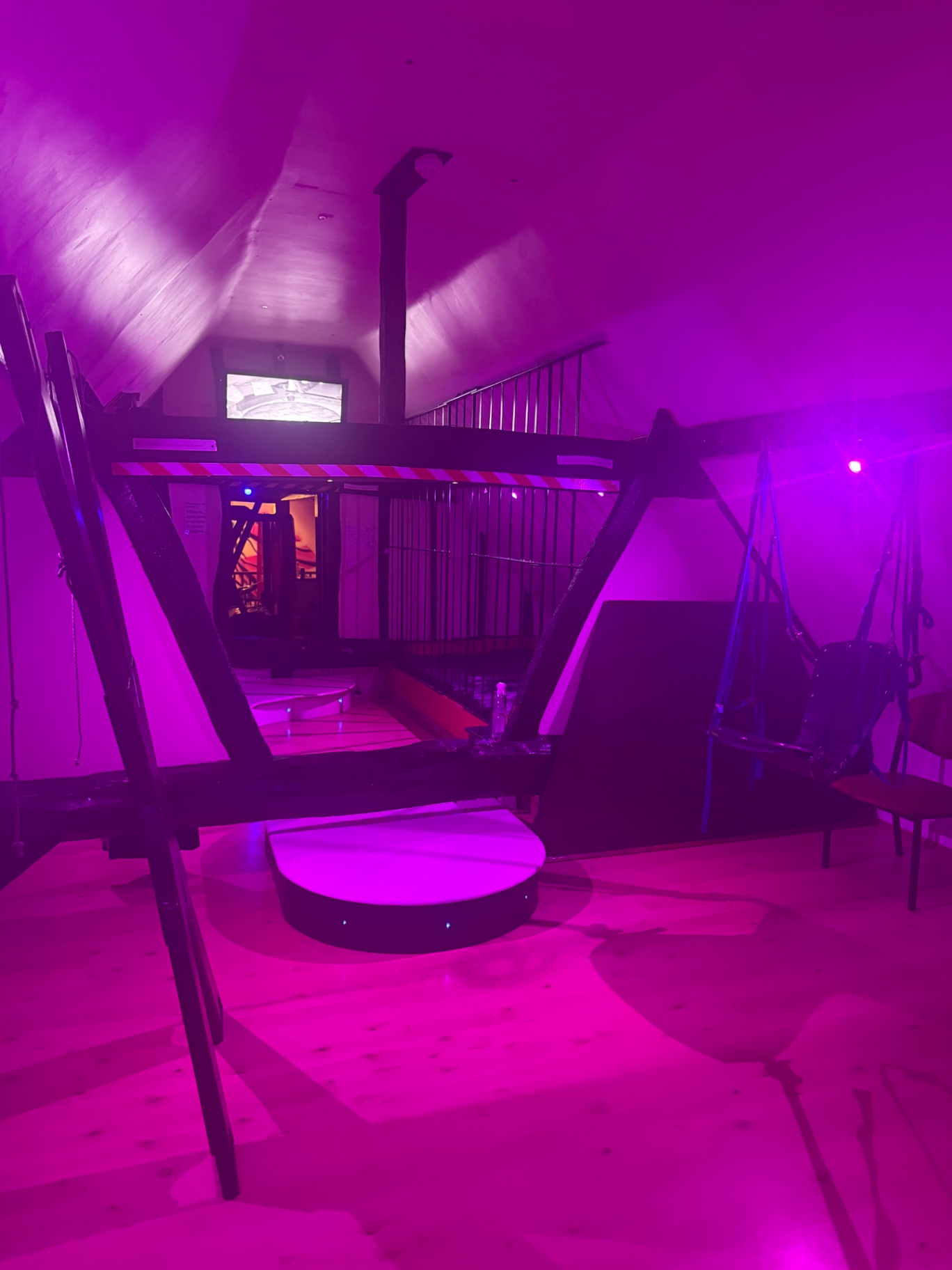 Upstairs play room bathed in purple light with a swing